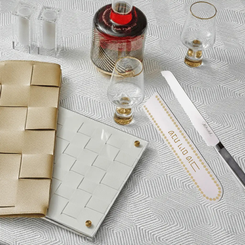 Tan leather knife blade cover by Waterdale Collection displayed with Shabbat serving items and challah board on white surface