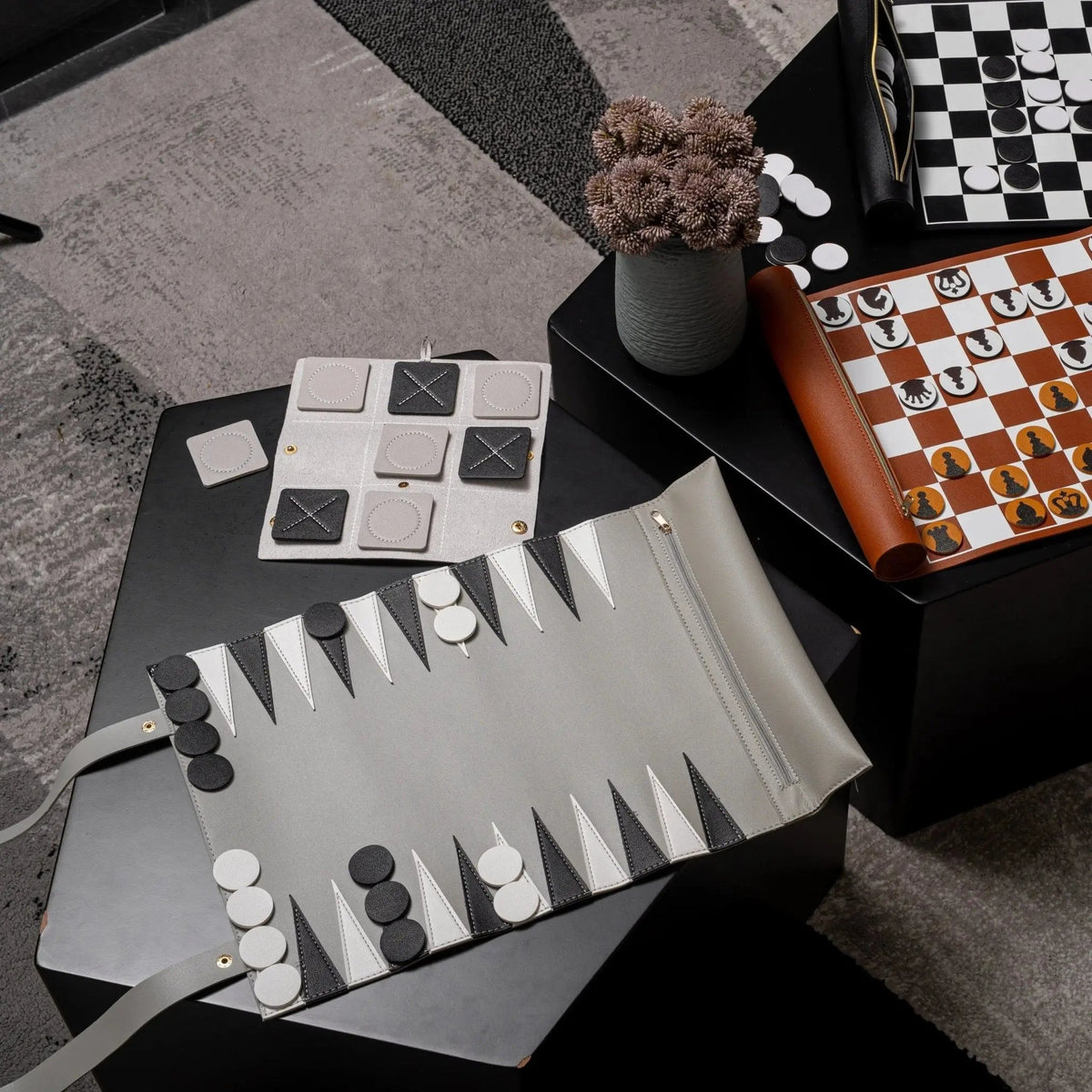 Leather backgammon game with brown case, white playing board, and black and white checkers arranged on surface with dice visible.