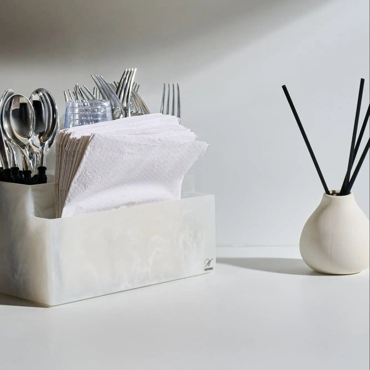 Cream teardrop reed diffuser by Waterdale Collection displayed with black reeds, styled next to kitchen utensil holder and home decor accessories.