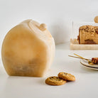 Amber resin cookie jar with rounded dome lid, filled with cookies, displayed with additional baked goods on a white surface.