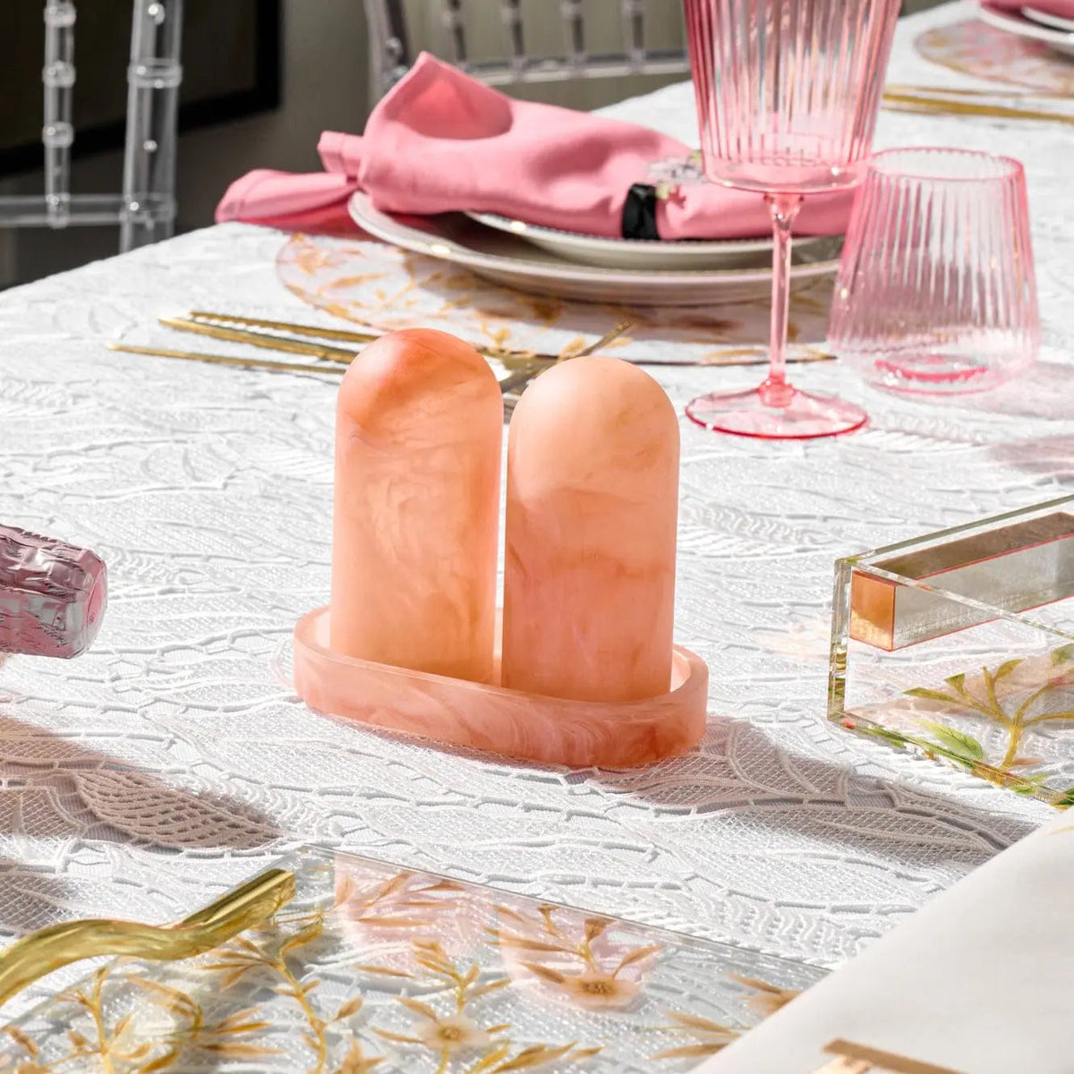 Coral resin salt shaker set with matching tray on white tabletop, displayed with place settings and dinnerware for entertaining and special occasions.