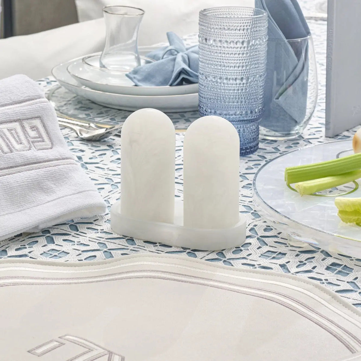 White resin salt shaker set with matching tray by Waterdale Collection, displayed on a patterned table setting with blue accents.