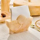 Round wooden resin napkin holder with natural finish, displayed on a neutral table setting with place cards and tableware for Pesach dining.