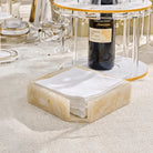Square resin napkin holder in cream and black marble design on Pesach table setting with dinnerware and gold accents