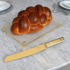 Waterdale Collection classic bread knife with serrated blade displayed next to fresh braided challah loaf on marble counter