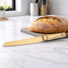 Waterdale Classic Bread Knife with serrated blade next to sliced loaf on marble countertop, wooden handle visible