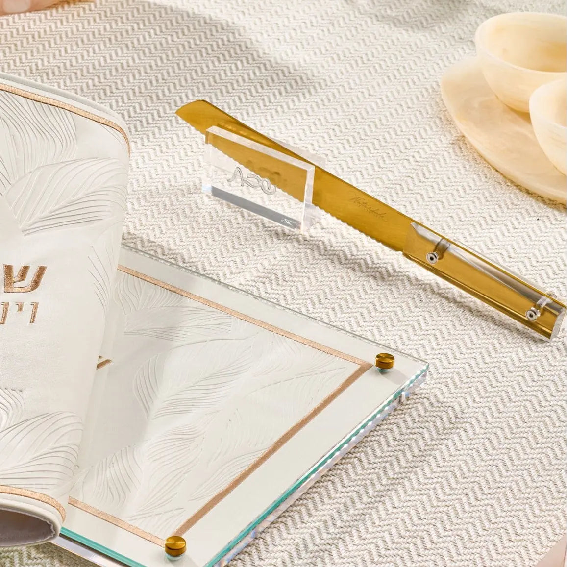 Gold-toned classic bread knife from Waterdale Collection displayed on white linen with place setting, showing serrated blade and elegant handle design.