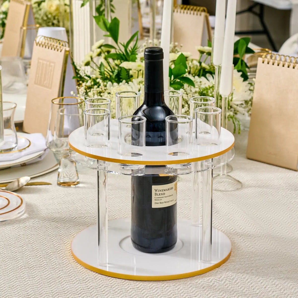 Classic round liquor set with marble top, brass accents, and black bottle holder displayed on white table with place settings.
