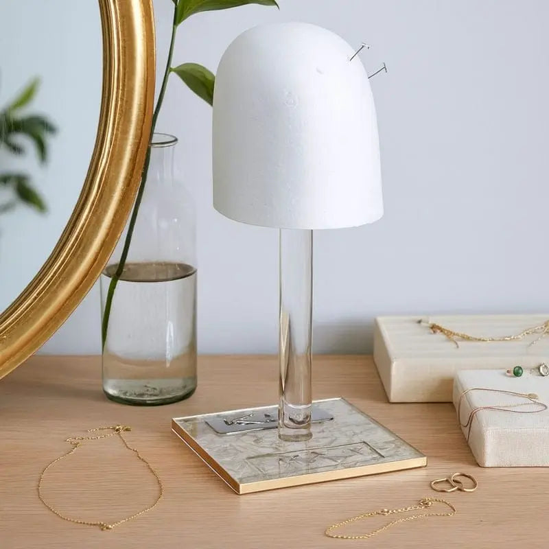 French Toile Lucite wig head with white dome and clear acrylic stand, displayed on desk with mirror and accessories.
