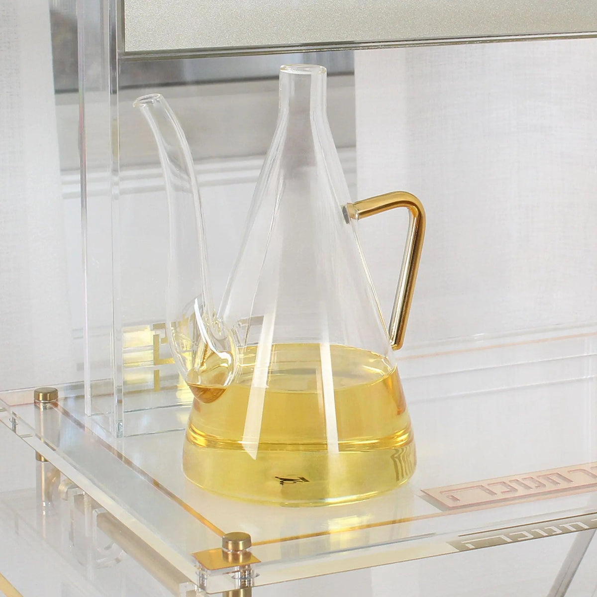 Glass oil jug filled with olive oil, its long spout ready to fill menorah cups for Chanukah