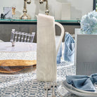 Cream resin pitcher by Waterdale Collection displayed on a patterned table runner with tableware and home décor.