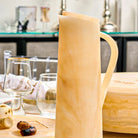 Cream-colored resin pitcher with handle displayed on kitchen counter next to glassware, from Waterdale Collection