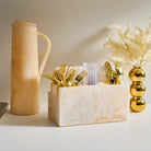 Tan resin pitcher by Waterdale Collection displayed with gold decorative accents and white marble container on white surface.