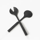 Pair of black resin salad servers with crossed handles and rounded serving ends, elegant serveware for entertaining and special occasions.