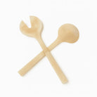 Crossed gold glitter resin salad servers with round bowl and fork ends on white background.