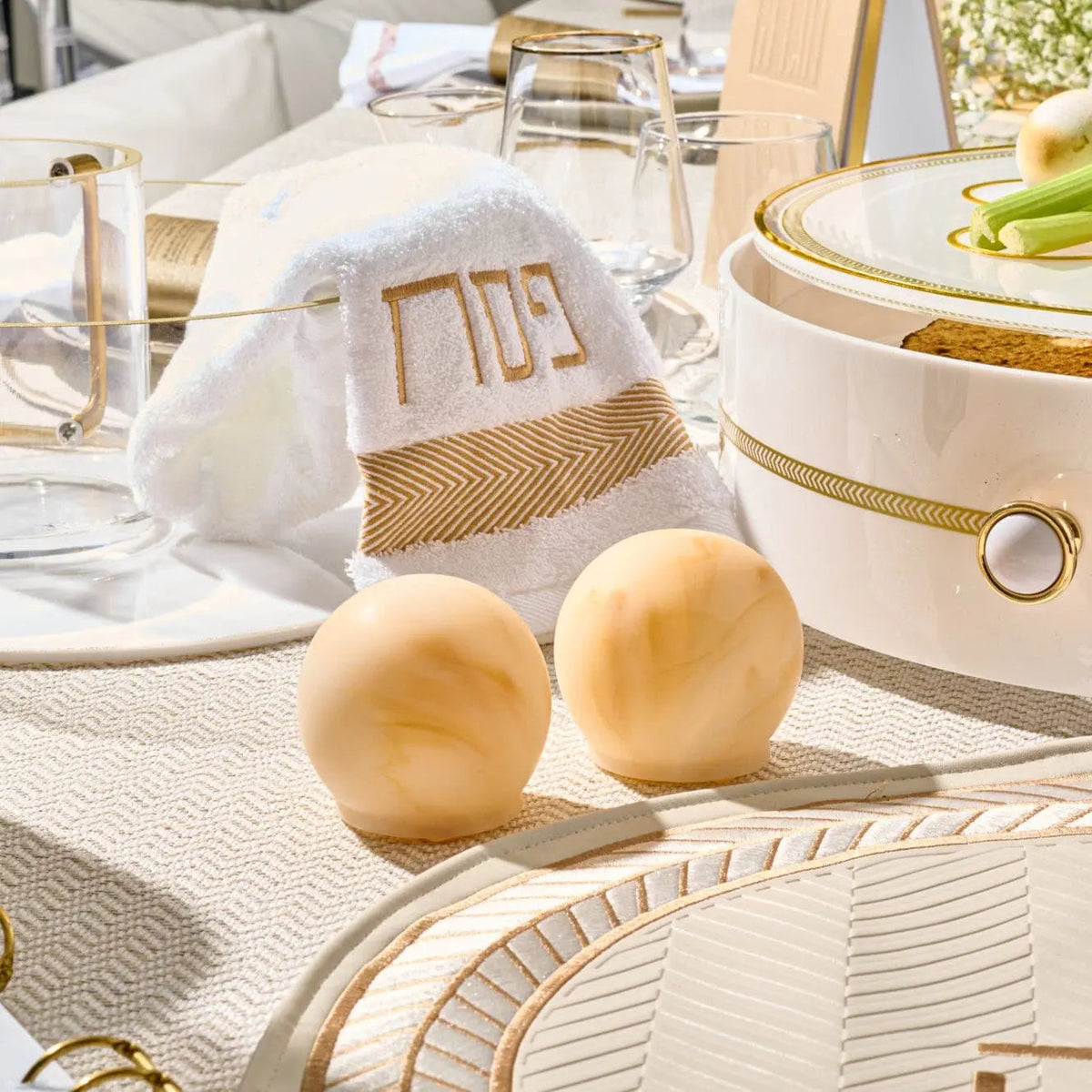 Pair of golden resin salt shakers on a white textured table setting with plates and linens from Waterdale Collection