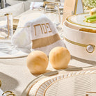 Pair of golden resin salt shakers on a white textured table setting with plates and linens from Waterdale Collection