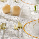 Pair of translucent amber resin salt shakers displayed on a marble table setting with gold-rimmed dinnerware and glassware.