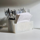 White resin silverware caddy holding various utensils and napkins, modern tabletop organizer for kitchen or dining.