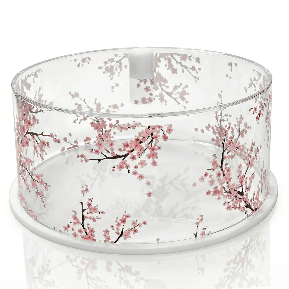 Clear glass round cake dome with delicate cherry blossom design in soft pink, perfect for serving and displaying baked goods.