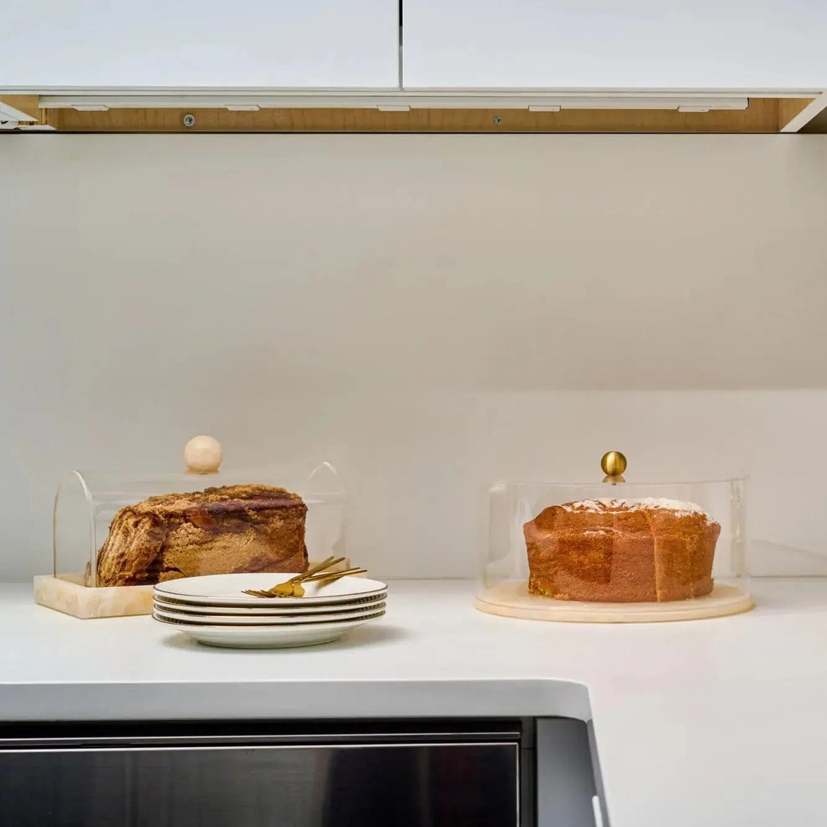 Small rectangular resin cake dome by Waterdale Collection displayed with a layered cake, featuring a warm amber tone and elegant design for serving and storage.