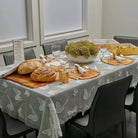 Onyx Butterfly Tablecloth with gray and white pattern displayed on table set with bread, salads, and dishes for Shabbat dinner.