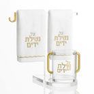 White towel and cup stand with gold accents and Hebrew text, featuring a ring holder for bathroom or vanity display.